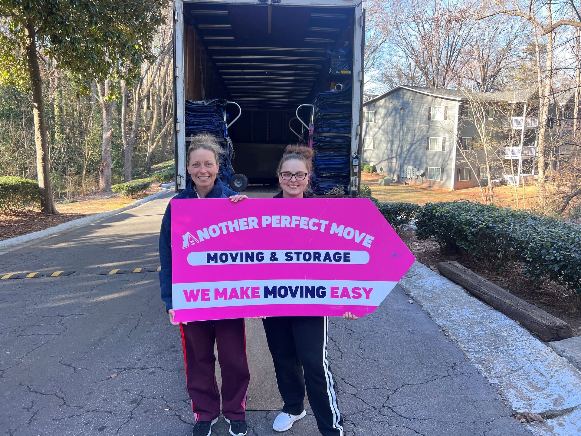 Two satisfied customers with an Another Perfect Move sign